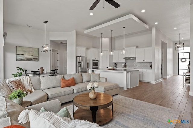 living area with recessed lighting, visible vents, light wood-style flooring, and ceiling fan with notable chandelier