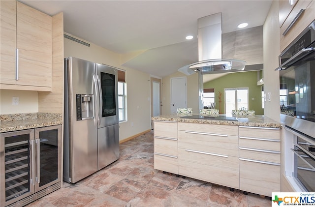 kitchen featuring beverage cooler, island range hood, light stone countertops, appliances with stainless steel finishes, and light brown cabinetry