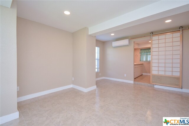 unfurnished room featuring a barn door and a wall mounted air conditioner