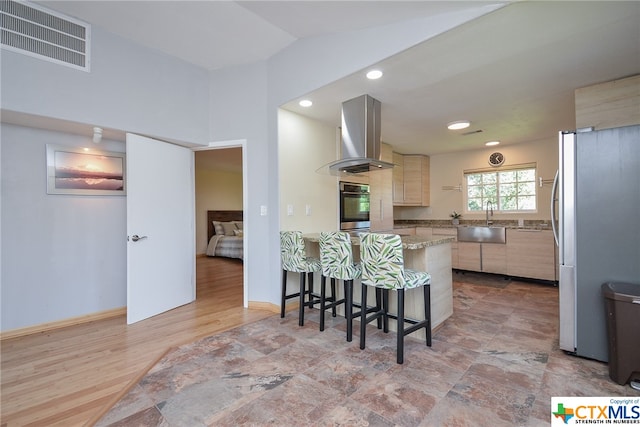 kitchen featuring refrigerator, sink, oven, wall chimney range hood, and light brown cabinetry