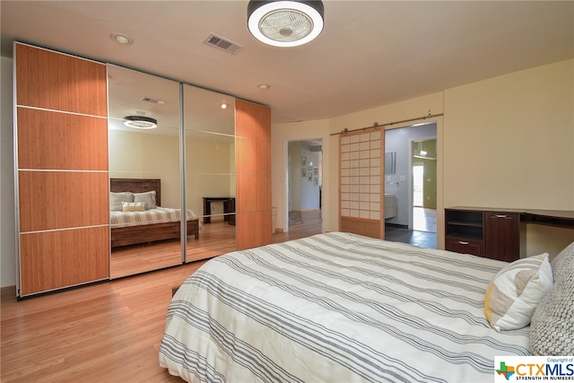 bedroom featuring a barn door, a closet, and light wood-type flooring