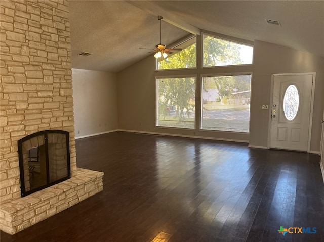 unfurnished living room with a textured ceiling, vaulted ceiling with beams, a stone fireplace, and dark wood-type flooring