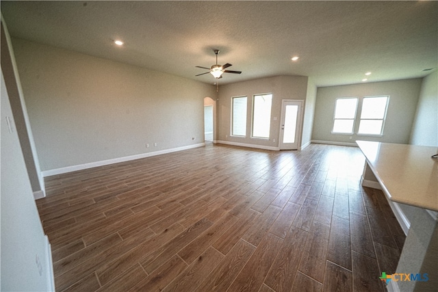 unfurnished living room featuring a textured ceiling, dark hardwood / wood-style flooring, and ceiling fan