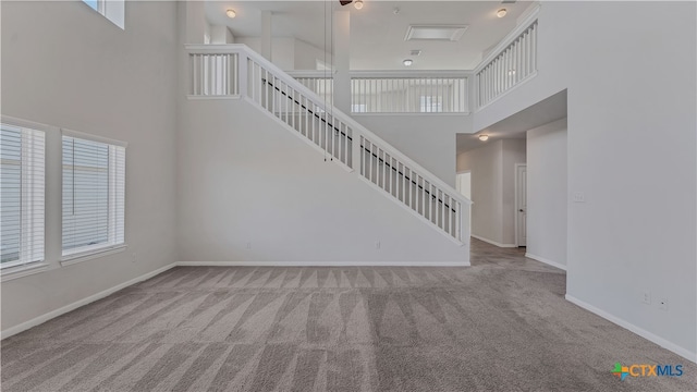 unfurnished living room with a towering ceiling and light colored carpet