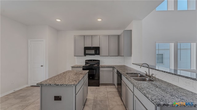 kitchen featuring black appliances, light stone countertops, kitchen peninsula, and sink