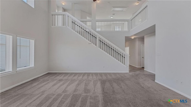 300 Jacks Pl, Seguin, TX 78155 - unfurnished living room featuring carpet, a towering ceiling, stairs, and baseboards