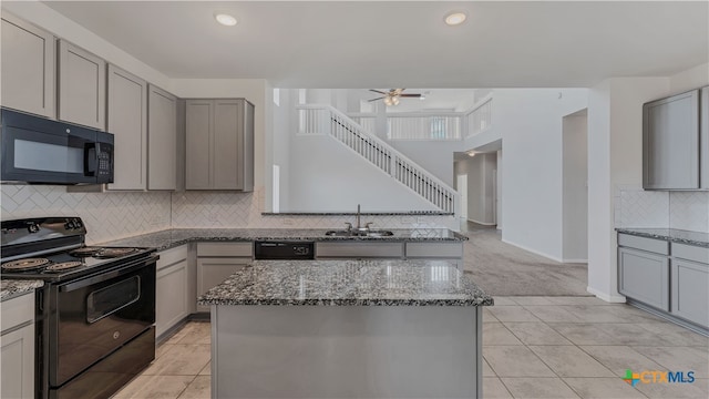 kitchen featuring black appliances, sink, a center island, and stone countertops