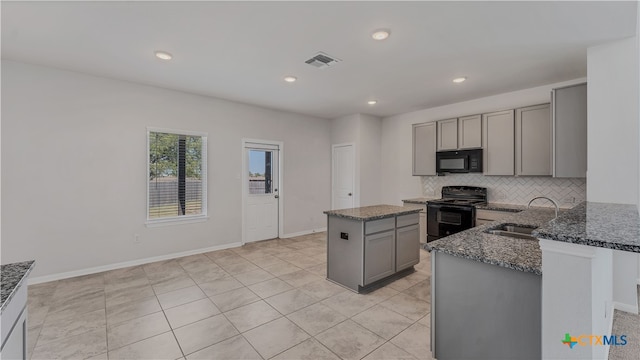 kitchen featuring black appliances, sink, gray cabinetry, a kitchen island, and dark stone countertops