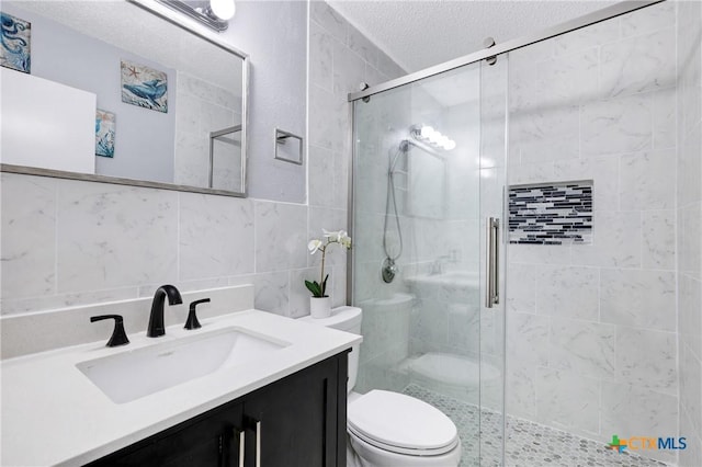 bathroom with tile walls, a textured ceiling, a shower with door, and toilet