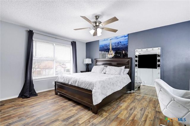 bedroom featuring dark wood-type flooring, a textured ceiling, and ceiling fan