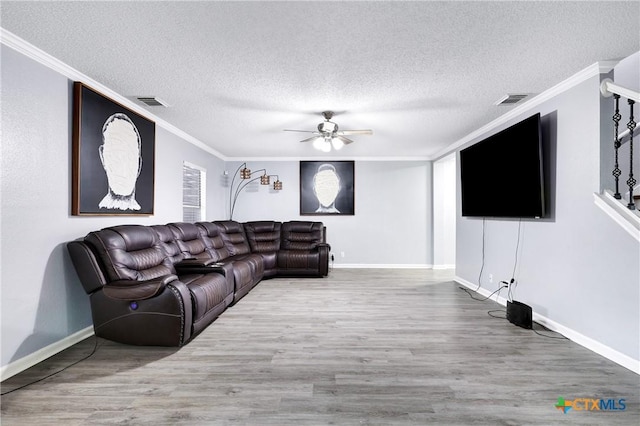 living room featuring ceiling fan, ornamental molding, wood-type flooring, and a textured ceiling