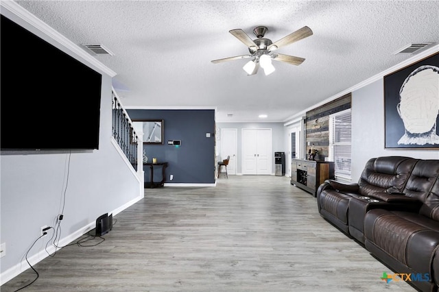 living room with crown molding, ceiling fan, light hardwood / wood-style floors, and a textured ceiling