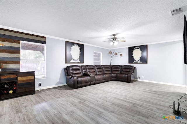 living room with hardwood / wood-style floors, ornamental molding, a textured ceiling, and ceiling fan