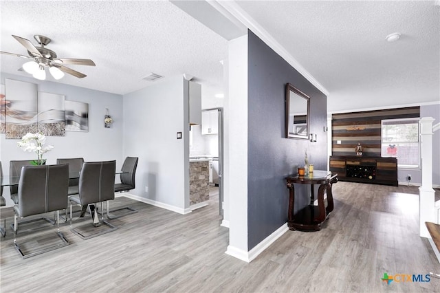 dining area with ceiling fan, ornamental molding, a textured ceiling, and light wood-type flooring