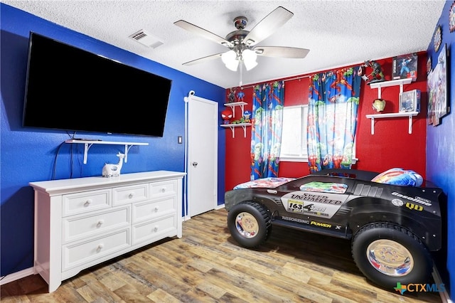 bedroom with ceiling fan, hardwood / wood-style floors, and a textured ceiling