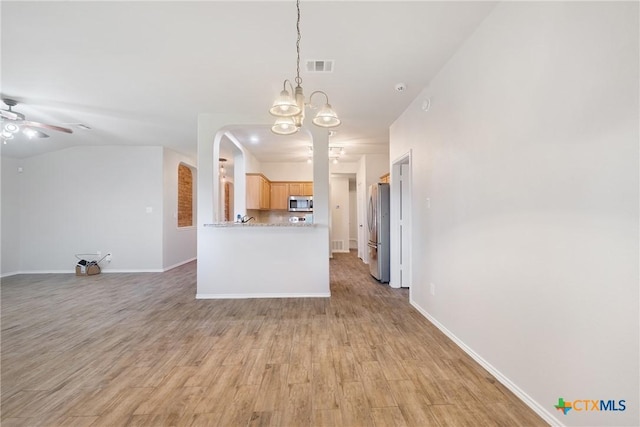 interior space featuring visible vents, ceiling fan with notable chandelier, light wood-type flooring, and baseboards