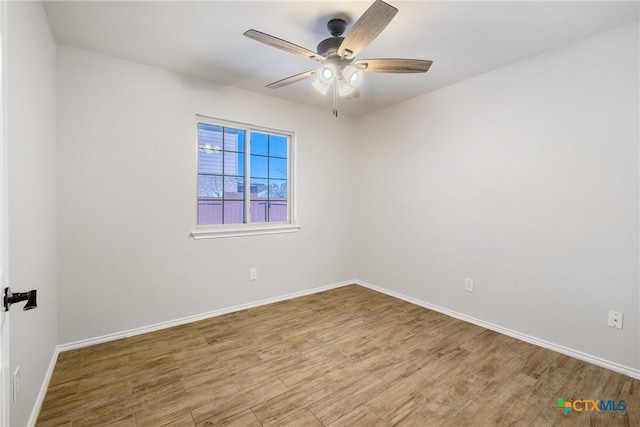 empty room with baseboards, wood finished floors, and a ceiling fan