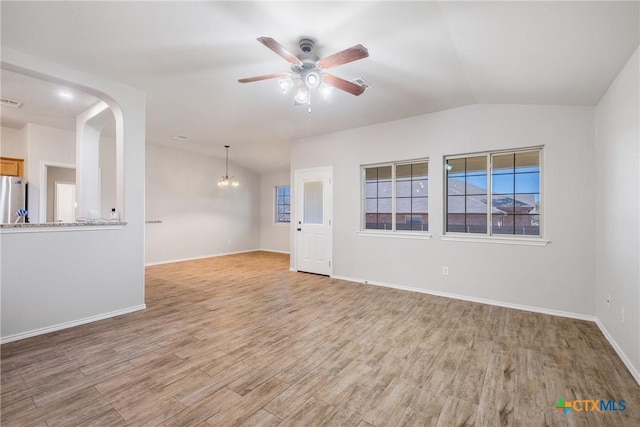 unfurnished room with light wood finished floors, visible vents, baseboards, vaulted ceiling, and ceiling fan with notable chandelier