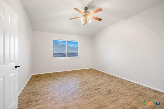 empty room with baseboards, lofted ceiling, wood finished floors, and a ceiling fan