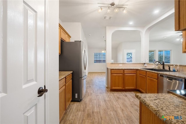 kitchen with visible vents, light wood-style flooring, brown cabinetry, stainless steel appliances, and a sink