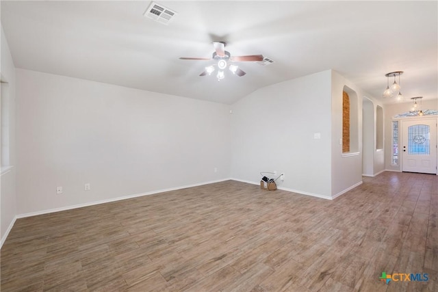 unfurnished room featuring wood finished floors, visible vents, baseboards, arched walkways, and ceiling fan