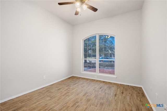 empty room featuring a ceiling fan, light wood-type flooring, and baseboards