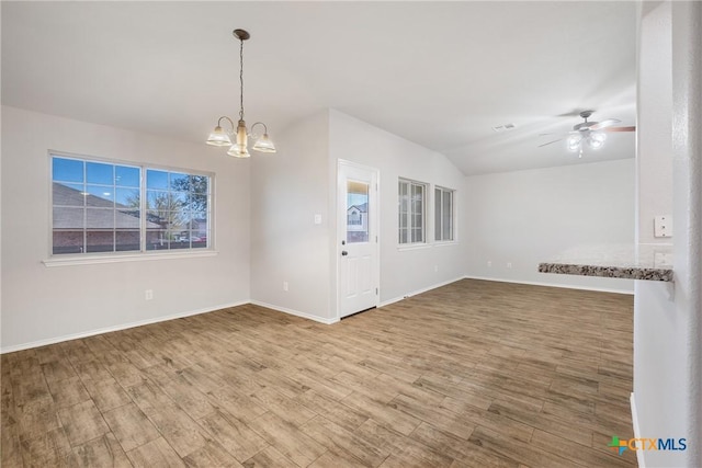 spare room featuring baseboards, lofted ceiling, wood finished floors, and ceiling fan with notable chandelier