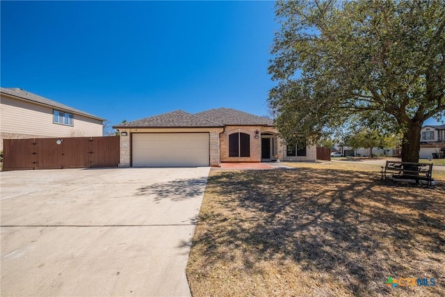 view of front of property featuring a gate, fence, a garage, and driveway