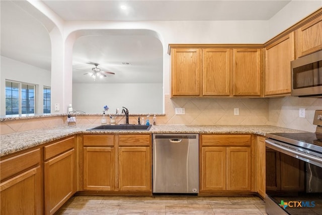 kitchen featuring a sink, stainless steel appliances, tasteful backsplash, and ceiling fan