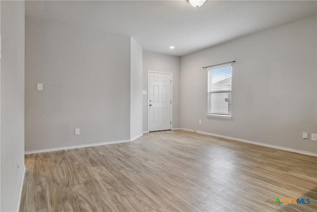 spare room featuring baseboards and light wood finished floors