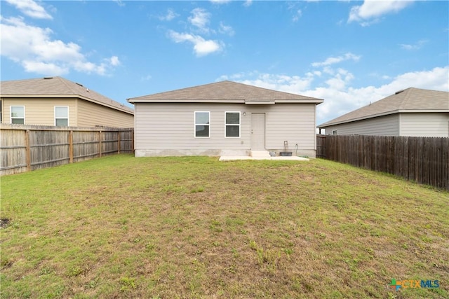 rear view of house featuring a fenced backyard and a yard
