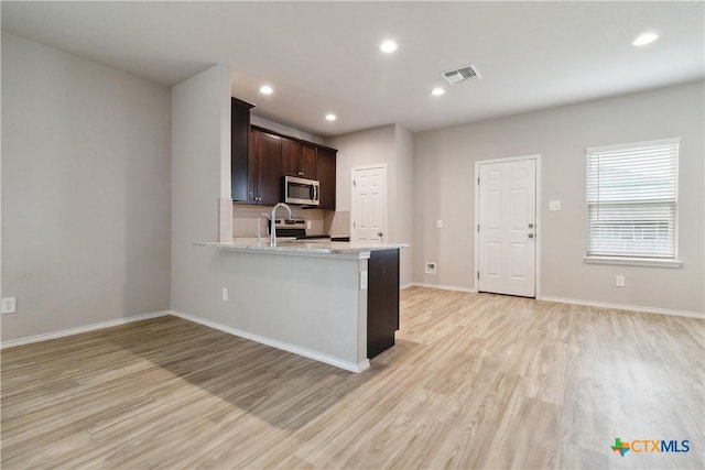 kitchen with light wood-type flooring, appliances with stainless steel finishes, dark brown cabinetry, and visible vents