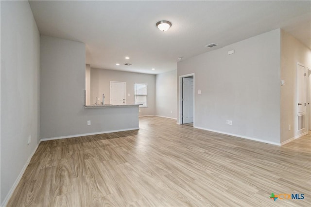 unfurnished living room with visible vents, light wood-style floors, and baseboards
