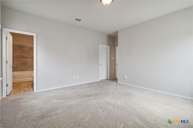 unfurnished bedroom with carpet flooring, baseboards, visible vents, and ensuite bathroom