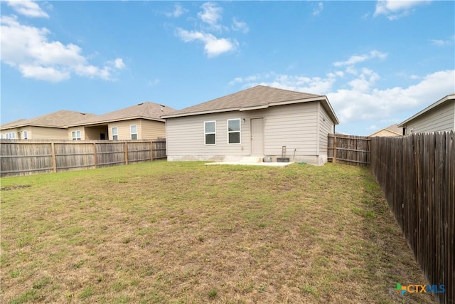 rear view of property featuring a fenced backyard and a lawn