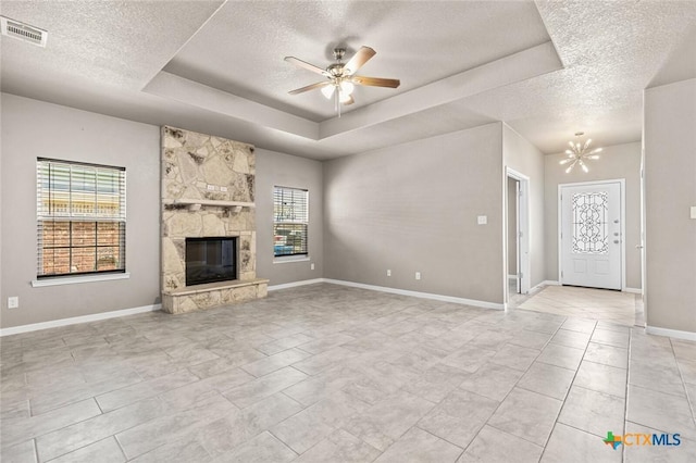 1536 Justice Dr, Copperas Cove, TX 76522 - unfurnished living room featuring a textured ceiling, a tray ceiling, a ceiling fan, a chandelier, and a stone fireplace