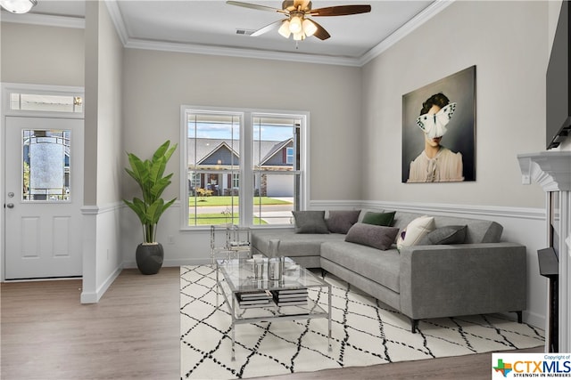 living room with ceiling fan, ornamental molding, and light hardwood / wood-style flooring