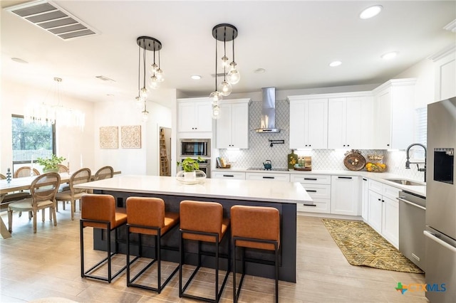 1428 Springwater, Canyon Lake, TX 78133 - kitchen with wall chimney range hood, stainless steel appliances, a center island, light countertops, and light wood-style floors