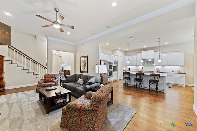living area featuring ornamental molding, recessed lighting, stairway, light wood finished floors, and a ceiling fan