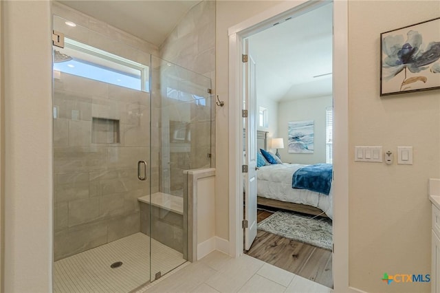 full bath with a stall shower, ensuite bathroom, wood finished floors, vanity, and vaulted ceiling