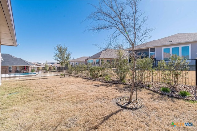 view of yard with a community pool, fence, and a residential view