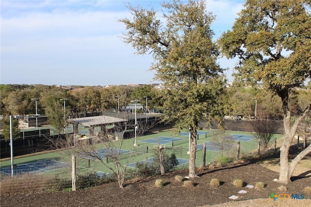 view of tennis court featuring community basketball court and fence