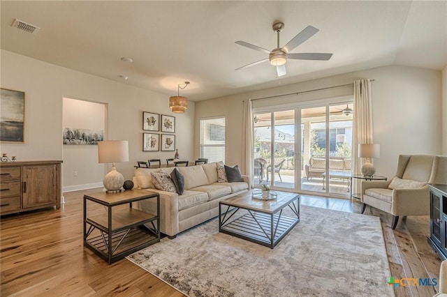 living area featuring vaulted ceiling, visible vents, a ceiling fan, and wood finished floors