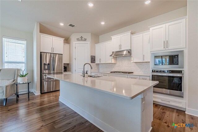 kitchen featuring visible vents, a sink, under cabinet range hood, appliances with stainless steel finishes, and a kitchen island with sink