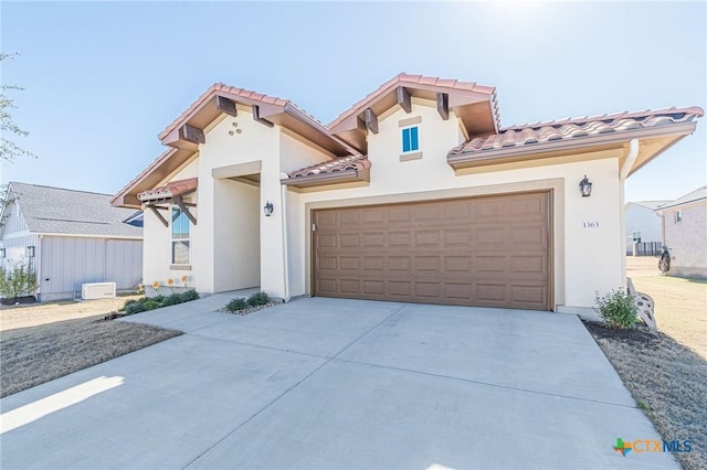 mediterranean / spanish home featuring stucco siding, a garage, driveway, and a tiled roof