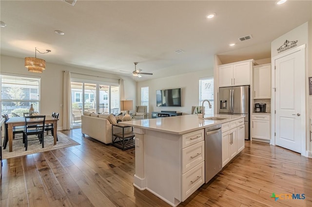 kitchen with a sink, appliances with stainless steel finishes, light countertops, and hardwood / wood-style flooring