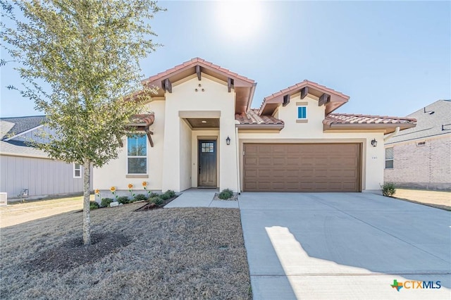 mediterranean / spanish-style house featuring stucco siding, concrete driveway, an attached garage, and a tiled roof