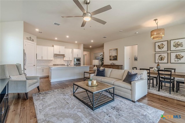 living room with recessed lighting, visible vents, ceiling fan, and light wood finished floors