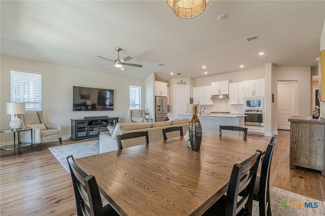 dining area with light wood finished floors, visible vents, and a healthy amount of sunlight