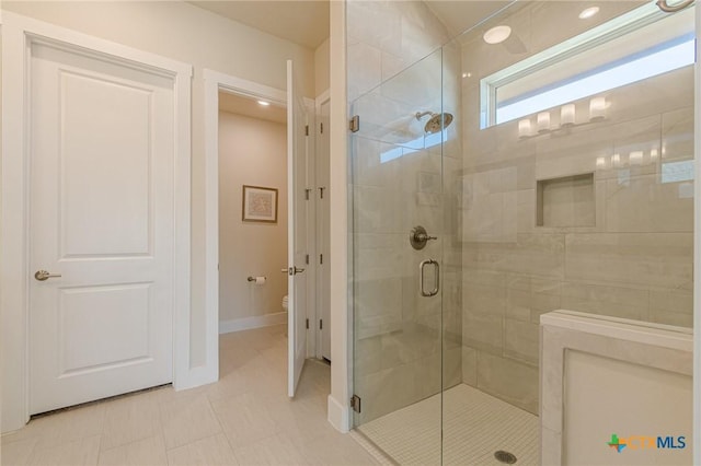 bathroom featuring baseboards, toilet, and a shower stall